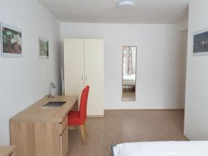 - une chambre avec un bureau et une chaise rouge dans l'établissement Apartmán 101, à Horní Maršov