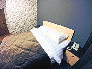 a bedroom with a bed with a phone on a night stand at Mini-Hotel Pulsar in Astana