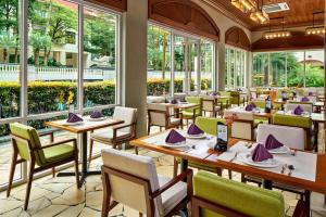 un restaurante con mesas, sillas y ventanas en Treetops Executive Residences en Singapur