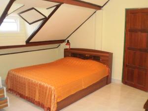 a bedroom with a bed with an orange bedspread at Phuket Green Home in Karon Beach