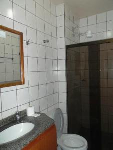 uma casa de banho com um WC, um lavatório e um espelho. em Temporada Ponta das Canas em Florianópolis