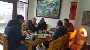 een groep mensen die rond een tafel zitten te eten bij Sapa Peaceful Hotel in Sa Pa