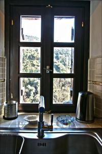 a kitchen with a sink and two windows at Koukourava Garden in Makrinítsa