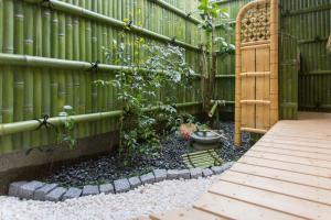 um jardim com uma cerca e um passadiço de madeira em Guest House Kyorakuya Kinkakuji em Quioto