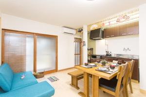 a living room with a table and a kitchen at Guest House Kyorakuya Kinkakuji in Kyoto