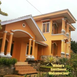 a yellow house with an arch in front of it at Wildan Homestay in Mangun