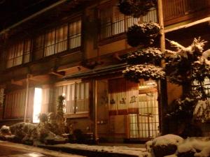 un edificio con nieve en el suelo delante de él en Yudanaka Onsen Yamazakiya, en Yamanouchi