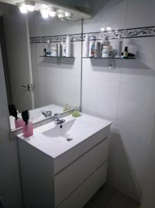 a white bathroom with a sink and a mirror at Apartamento primera línea de mar in Hospitalet de l'Infant