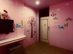 a room with a pink wall with a tree and a door at Funja Colorful Hotel in Taichung