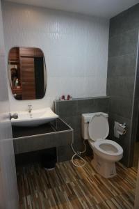 a bathroom with a toilet and a sink and a mirror at The Rhea in Udon Thani