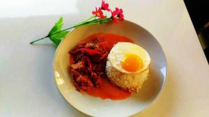 a plate of food with an egg on a table at Must Come Boutique Hotel in Ban Nam Khong