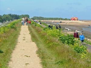 a group of people walking along a path next to a beach at Tolly House in Wells next the Sea