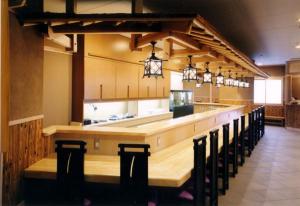 a restaurant with a long bar with black chairs at Hyuga Dai-ichi Hotel in Hyuga