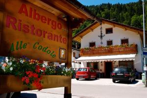 un panneau devant un bâtiment fleuri dans l'établissement Albergo Ristorante Alle Codole, à Canale dʼAgordo