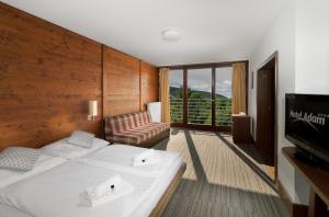 una camera d'albergo con un letto, un divano e una televisione di Hotel Adam a Špindlerův Mlýn