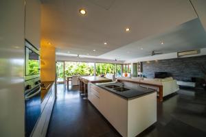 cocina abierta y sala de estar con pared de piedra. en Amertha Villa Dreamland, en Uluwatu