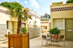a patio with a table and chairs and a palm tree at Almoria Hôtel & SPA in Deauville