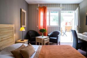 ドーヴィルにあるAlmoria Hôtel & SPAのベッド、デスク、椅子が備わるホテルルームです。