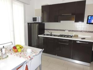 ビビオーネにあるIsolabella - Appartamentiのキッチン(黒いキャビネット、フルーツ付きのテーブル付)