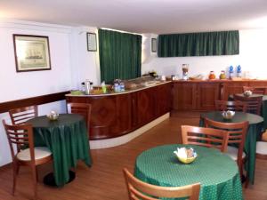 a restaurant with two tables and a kitchen with green curtains at Hotel Traghetto in Civitavecchia