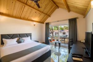 a bedroom with a large bed and a balcony at White Woods Resort, Morjim in Morjim