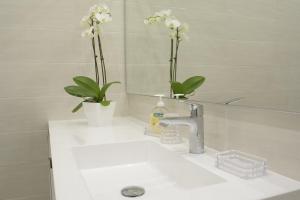 a bathroom sink with two flowers and a mirror at Villa Thomas in Imperia +30 photos