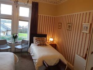 a bedroom with a bed and a desk and a window at Seaview Wellness Retreat and Guesthouse in Carnoustie