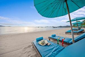 a beach with two lounge chairs and an umbrella at Pinnacle Samui Resort in Mae Nam