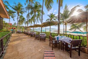 a restaurant on the beach with tables and umbrellas at Pinnacle Samui Resort in Mae Nam