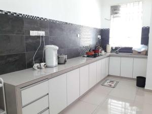 een keuken met witte kasten en een zwarte muur bij OOI Homestay Alor Setar in Alor Setar
