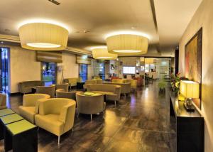 uma sala de espera com cadeiras, mesas e luzes em Hotel Cruise em Lucino