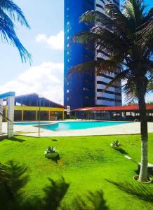 uma piscina num parque com palmeiras e um edifício em Residence Van Piaget em Fortaleza