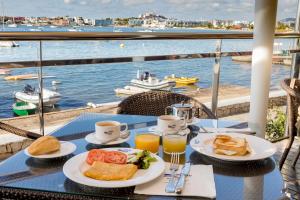 a table with plates of food and drinks and a view of the water at Hotel Simbad Ibiza in Talamanca