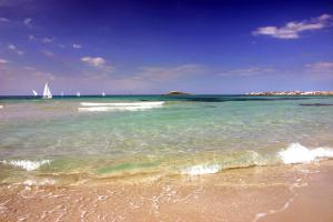 a sandy beach with a sail boat in the ocean at Hotel Sirenetta in Isola delle Femmine