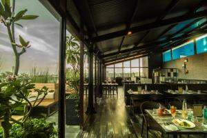 a restaurant with tables and chairs and large windows at Roopa Elite in Mysore