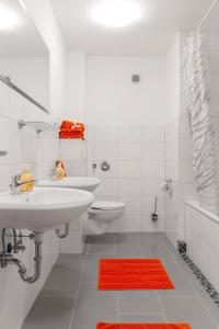 a white bathroom with two sinks and a red rug at Apartment Breite Str. 83 in Witten