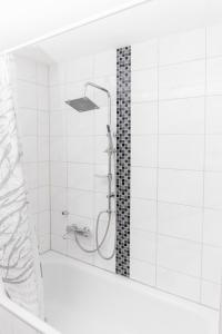 a shower in a white tiled bathroom with a shower head at Apartment Breite Str. 83 in Witten