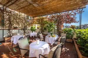 un restaurante con mesas blancas, sillas y plantas en Hotel Emma Small Luxury Hotel en Florence
