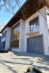 a white house with a balcony and a garage at Hotel Good Luck in Kutaisi