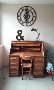 a desk with a chair and a clock on the wall at Le Jardin de la Reyssouze in Gorrevod