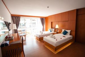 ein Hotelzimmer mit zwei Betten und einem Schreibtisch in der Unterkunft Phi Phi Harbour View Hotel-SHA Extra Plus in Ko Phi Phi