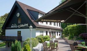 a hotel with tables and chairs and an umbrella at Hotel Peiler Garni in Iserlohn