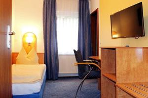 a hotel room with a bed and a flat screen tv at Hotel Peiler Garni in Iserlohn