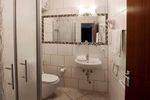 a bathroom with a sink and a toilet and a mirror at Hotel Peiler Garni in Iserlohn
