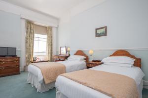 ein Hotelzimmer mit 2 Betten und einem TV in der Unterkunft The Queens Hotel in Penzance