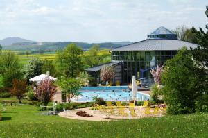 a swimming pool with a building in the background at Land- und Aktivhotel Altmühlaue in Bad Rodach