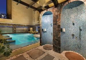 a bathroom with a pool and a stone wall at Wyndham Grand Regency Doha in Doha