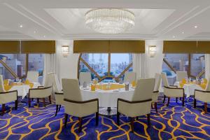 a dining room with a table and chairs and windows at Makkah Towers in Mecca