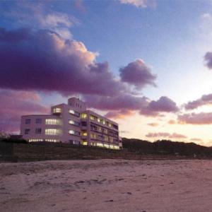 un edificio sulla spiaggia con il tramonto sullo sfondo di Senjoen a Shimokō