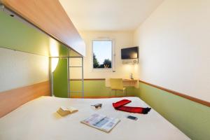 コーヌ・クール・シュル・ロワールにあるHotel Ibis Budget Cosne Sur Loireのベッド、デスク、窓が備わる客室です。